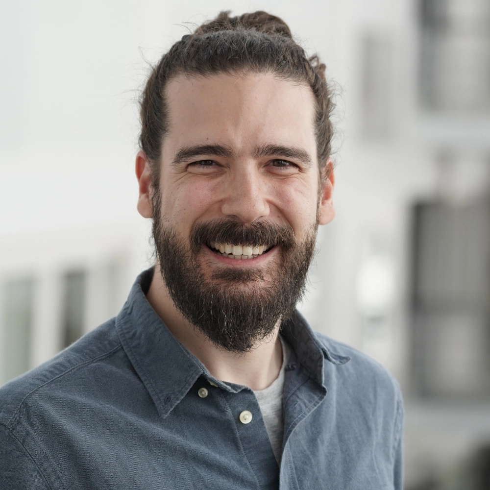 Portrait of a smiling man with beard and hair in a bun