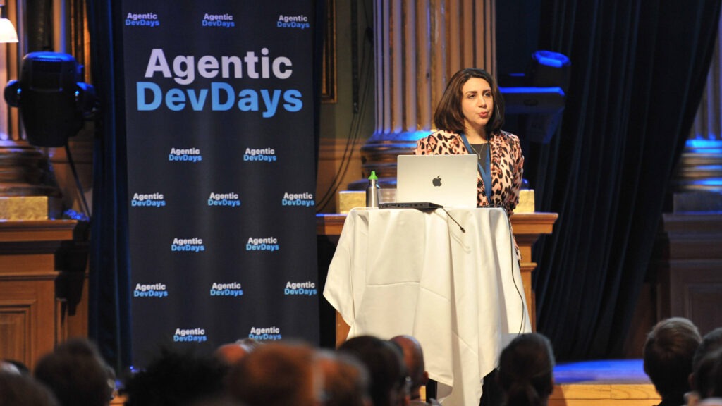 Woman speaking on stage with laptop, roll-up